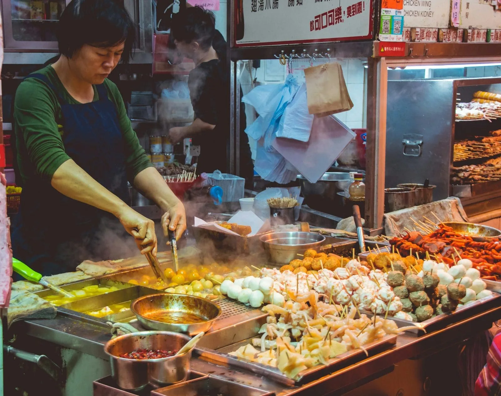 Street food vendor preparing skewers and fish balls at a night market stall