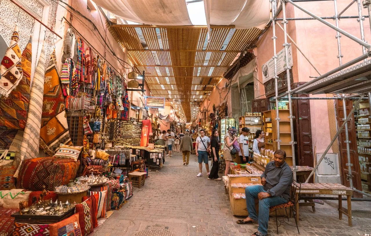 Covered market alley in the Marrakech medina lined with rug, lantern, and spice stalls
