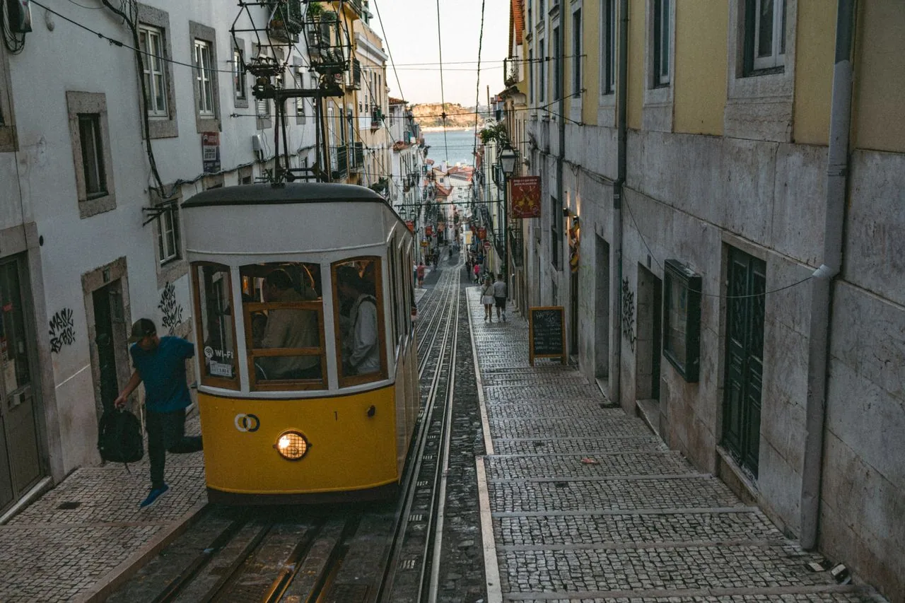 Lisbon's yellow Tram 28 climbing a hill street in the Alfama quarter, where a written Portuguese allergy card helps at neighborhood restaurants