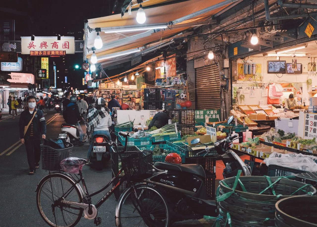 Night market street lined with food stalls and parked motorbikes in Taipei, Taiwan