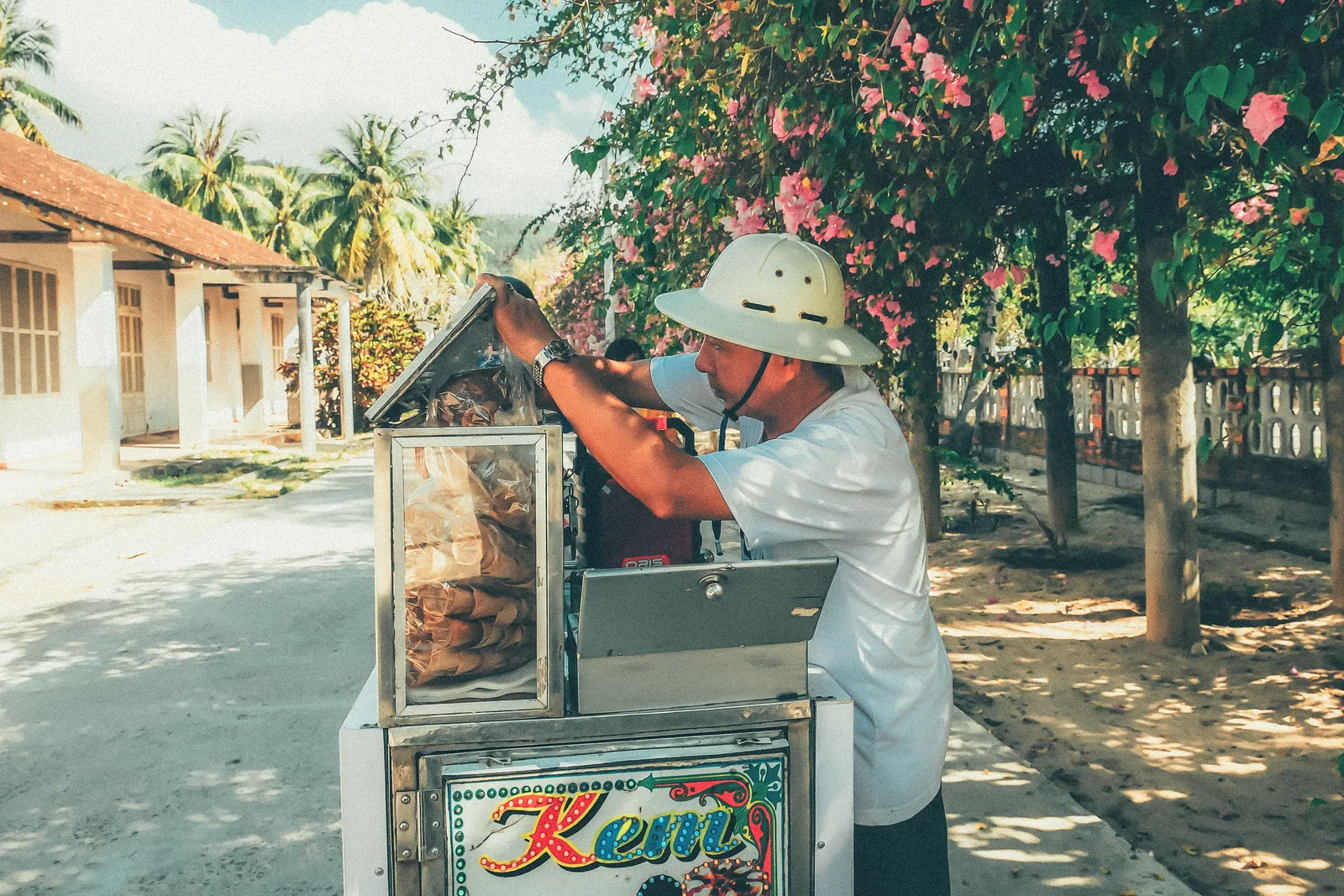 Vietnamese street vendor opening an ice cream cart labeled 'Kem'