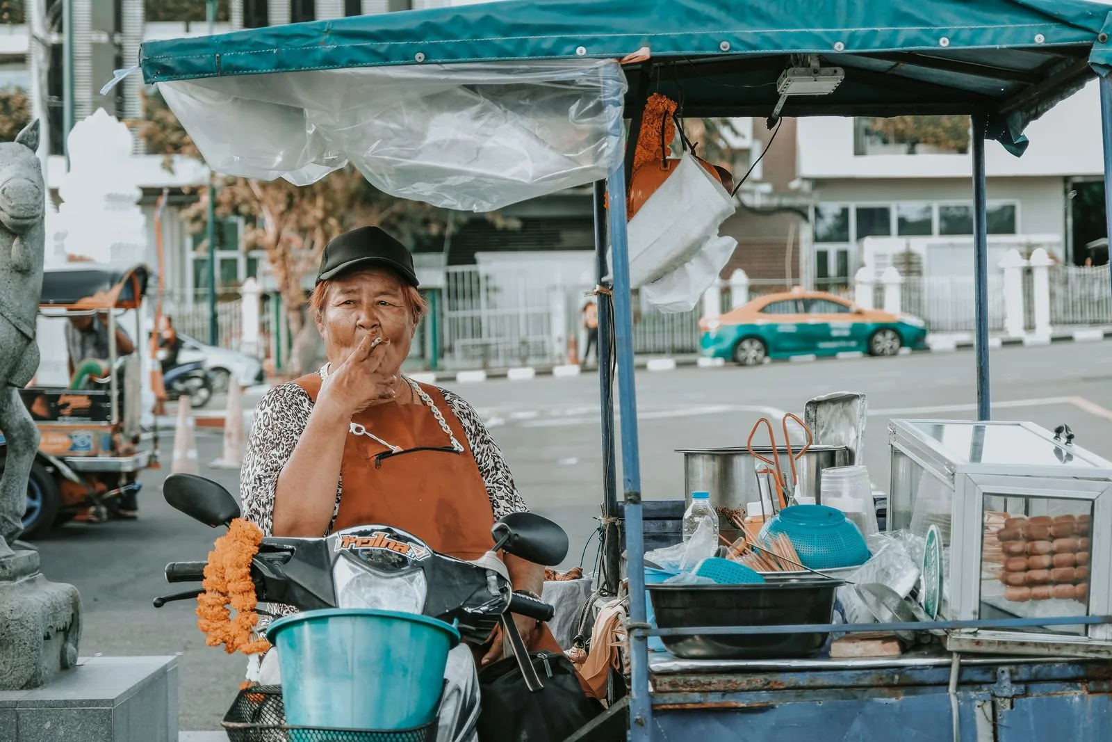 Street food vendor cart in Bangkok, with a Bangkok taxi visible in the background