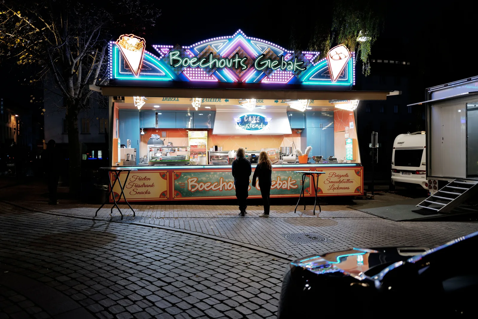 Illuminated food stall on a cobblestone street at night