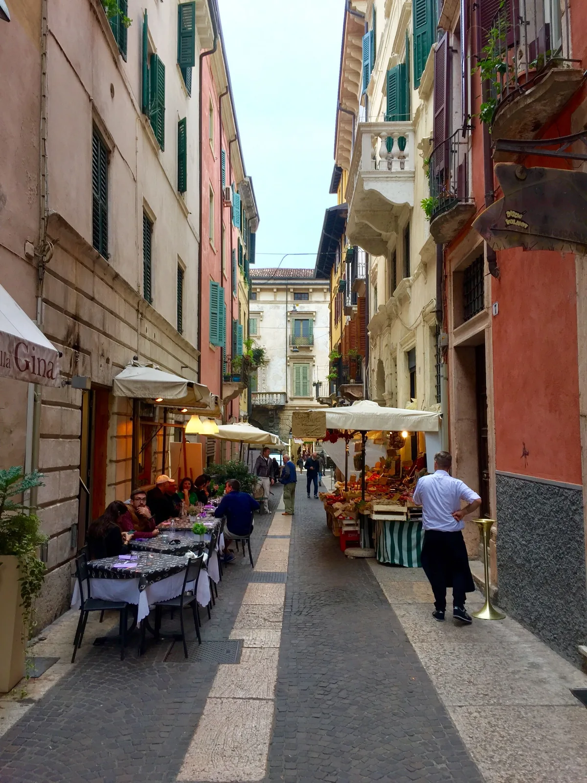 Narrow street with outdoor restaurant seating in Verona, Italy