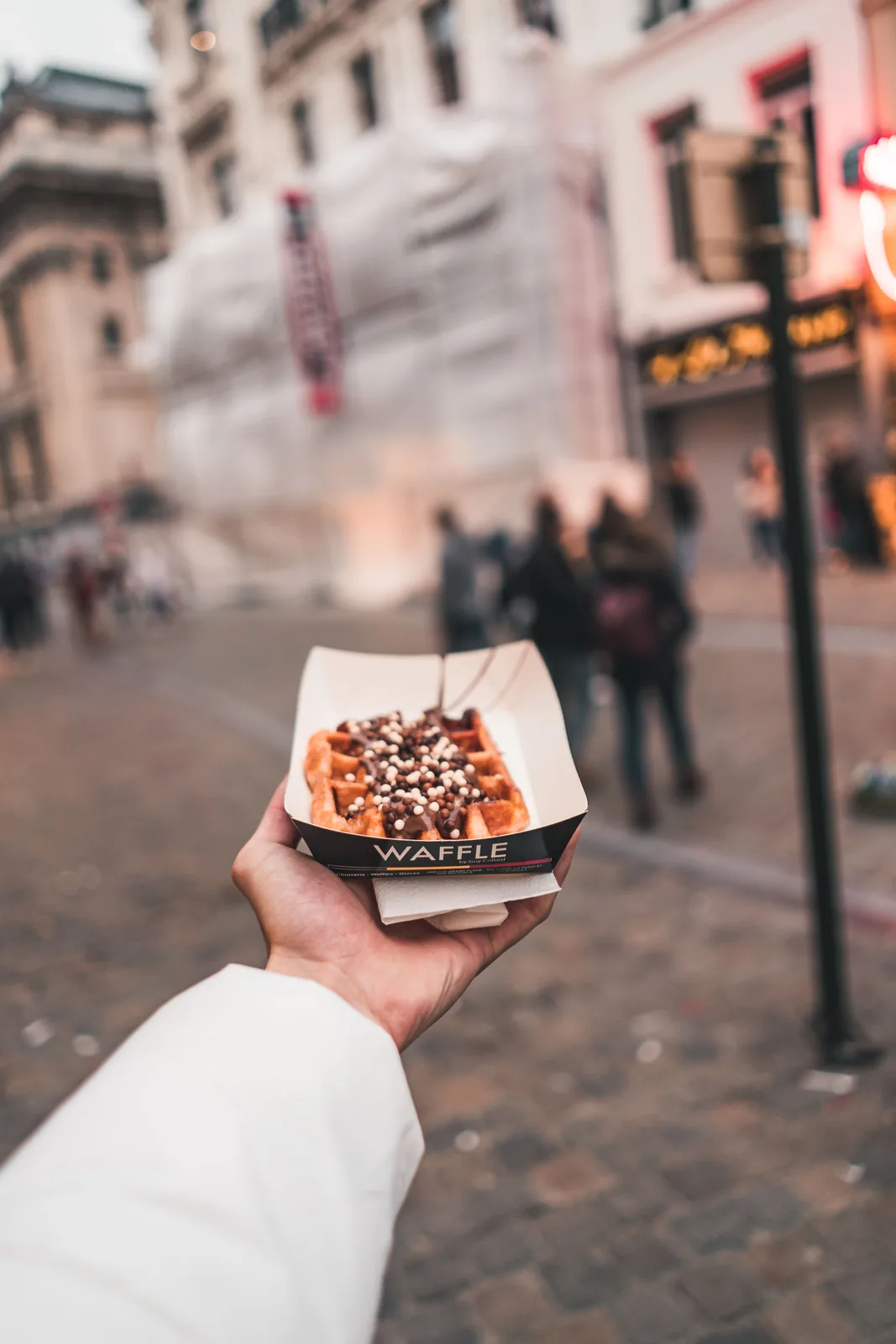 Hand holding a box of street food at dusk