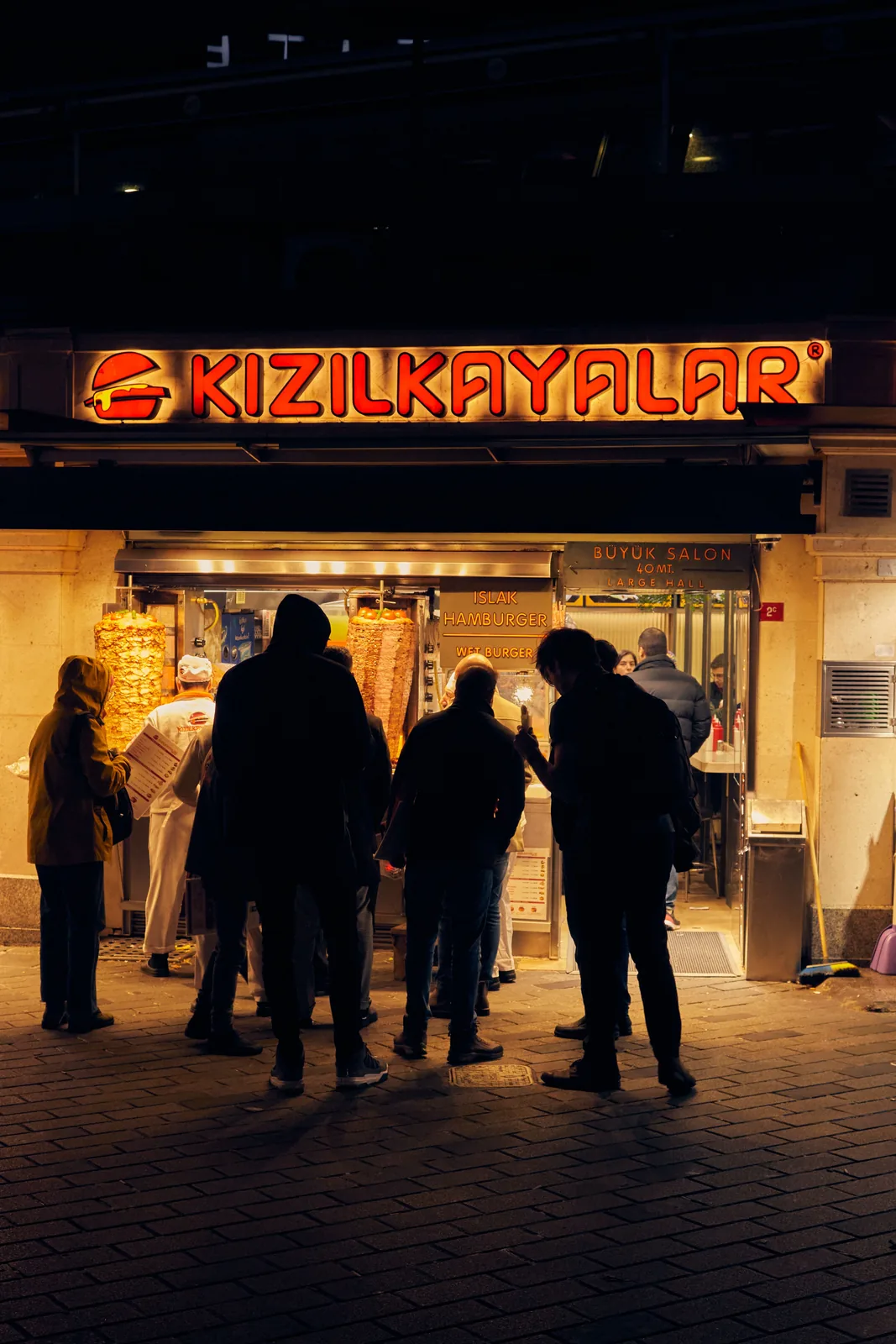Pedestrians walking beneath neon signs at night